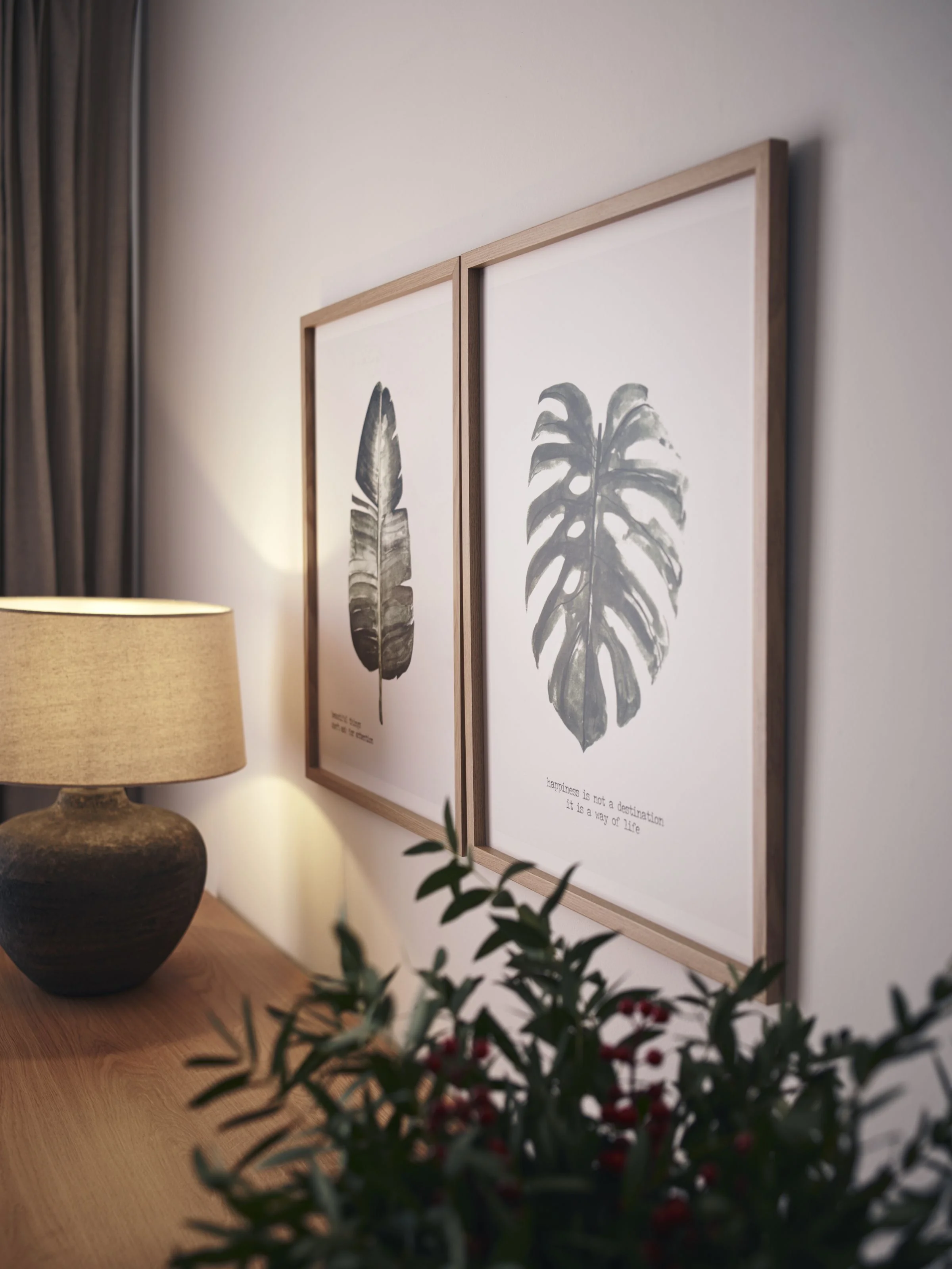 ceramiczna lampa i drewniane ramki nad drewnianą komodą